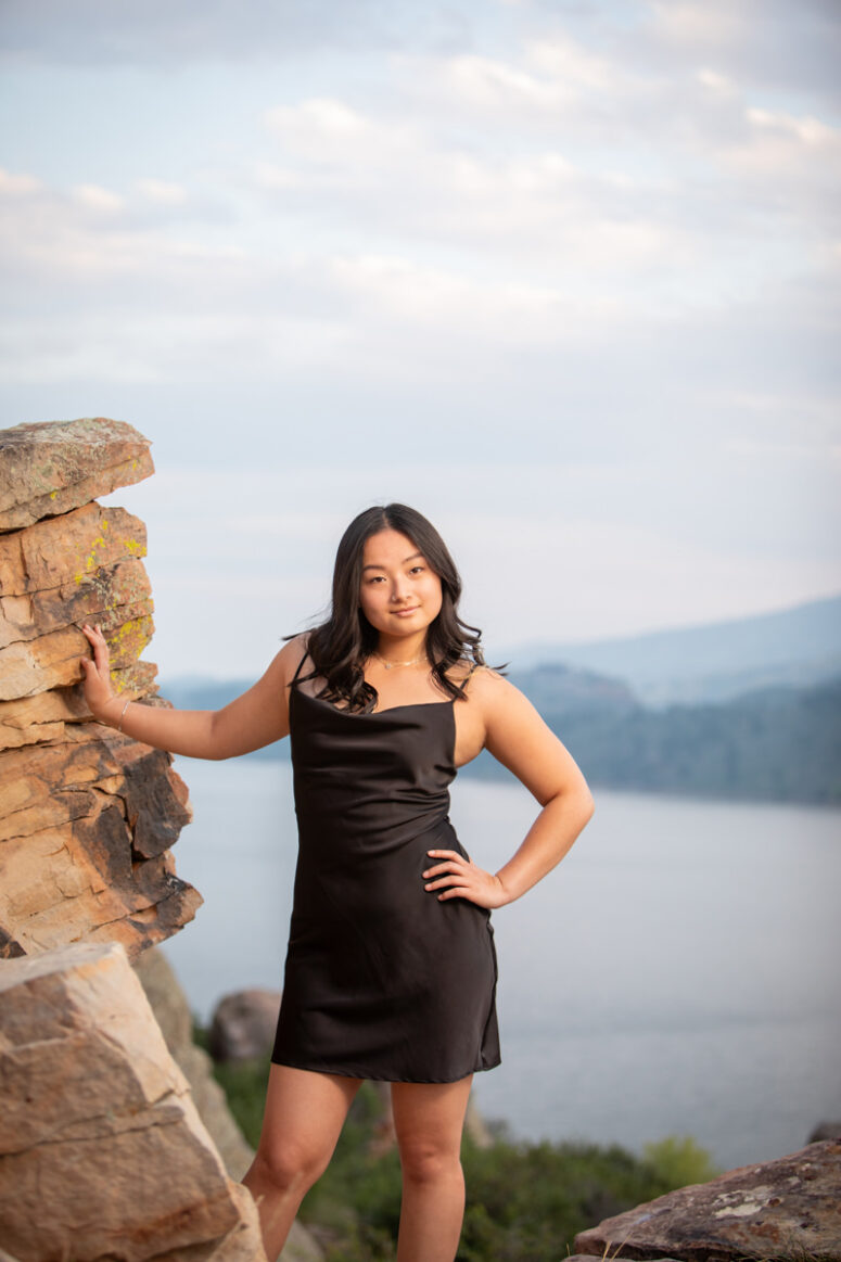 Girl stand against tall rock above Horsetooth Reservoir.