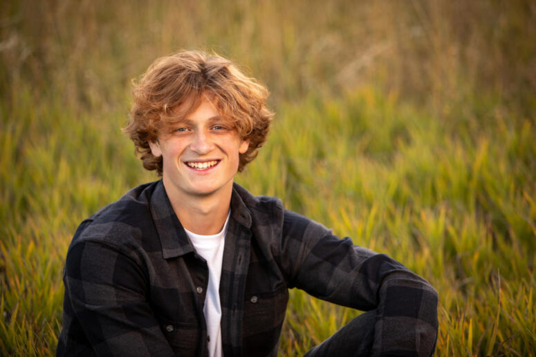 High school senior boy with red hair in green grass.